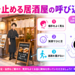 居酒屋の入口でスタッフが適切な距離を保ち、看板と笑顔で通行人へ自然に案内している図